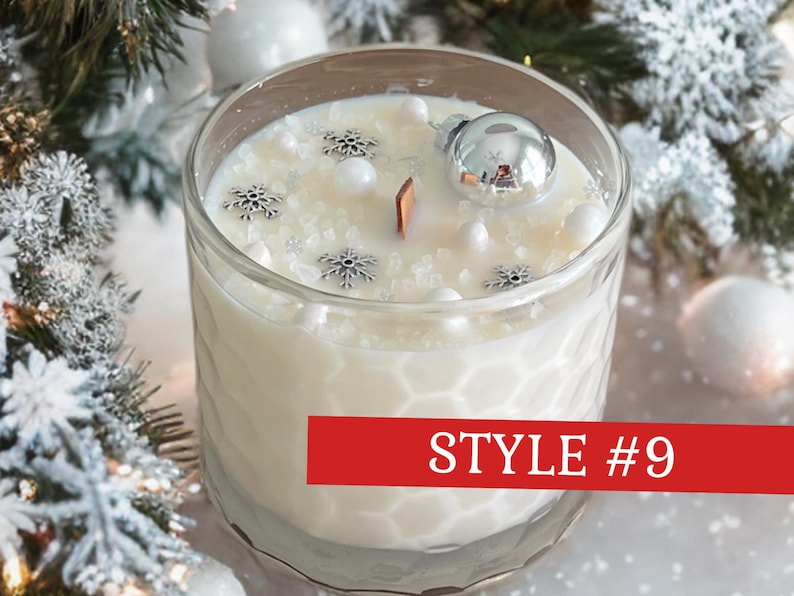 May include: A white candle in a clear glass jar with a honeycomb texture. The wax surface is decorated with silver snowflake charms, white beads, and a small silver ornament. A wooden wick is centered. A red banner displays the text STYLE #9.