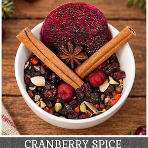 May include: A white bowl filled with a loose leaf tea blend containing dried cranberries, sliced dragon fruit, star anise, cinnamon sticks, cardamom pods, and almond slivers. The text CRANBERRY SPICE is printed at the bottom of the image.