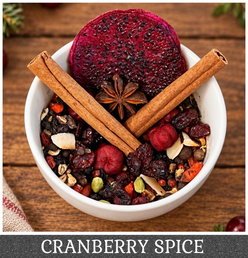 May include: A white bowl filled with a loose leaf tea blend containing dried cranberries, sliced dragon fruit, star anise, cinnamon sticks, cardamom pods, and almond slivers. The text CRANBERRY SPICE is printed at the bottom of the image.