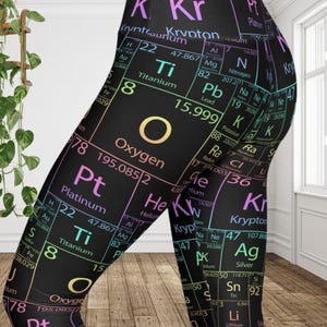 May include: Black leggings featuring a periodic table design with elements like Oxygen, Platinum, and Krypton in various colors. The leggings have a form-fitting design and are made of a stretchy material.