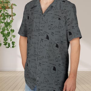 Può includere: Camicia grigia con bottoni con un motivo nero ripetuto di simboli matematici, inclusi simboli pi, forme geometriche ed equazioni. La camicia a maniche corte ha un colletto classico e una tasca sul petto.
