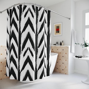 May include: A white shower curtain with a bold black chevron pattern. The design features thick, brushstroke-style chevrons arranged in vertical rows. The curtain hangs from a curved, silver-colored shower rod, creating a modern bathroom aesthetic.