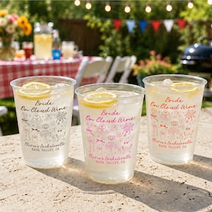 Könnte beinhalten: Drei durchsichtige Kunststoffbecher gefüllt mit Eis und Zitronenscheiben. Jeder Becher zeigt den Text Bride On Cloud Wine, Olivia's Bachelorette, NAPA VALLEY, CA sowie kleine Illustrationen von Kuchen, Ringen und Schleifen in Schwarz, Pink und Rot.