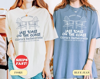 May include: Ivory and blue jean t-shirts with a graphic design. The design includes two beach chairs, the text "August 2025", and "Last Toast on the Coast, Olivia's Bachelorette, Charleston, South Carolina."