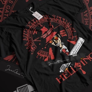 Puede incluir: Camiseta negra con un gráfico rojo de un personaje de Hellsing, con sombrero y gafas de sol, sosteniendo una pistola. El diseño incluye el texto "HELLSING" y otro texto en un patrón circular. Una etiqueta está adjunta.