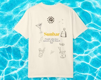 May include: Cream-colored t-shirt featuring a graphic of a sun, birds, and cocktail illustrations. The text "Sunbar" is displayed with the tagline "People who love sunsets at the beach bar."