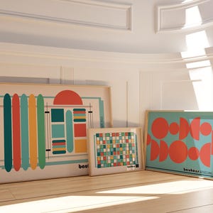 Może przedstawiać: Trzy oprawione wydruki artystyczne z geometrycznymi wzorami. Największy wydruk przedstawia pionowe paski w kolorze morskim, czerwonym, pomarańczowym i żółtym. Środkowy wydruk ma wzór kratki, a trzeci pomarańczowe półkola na turkusowym tle.