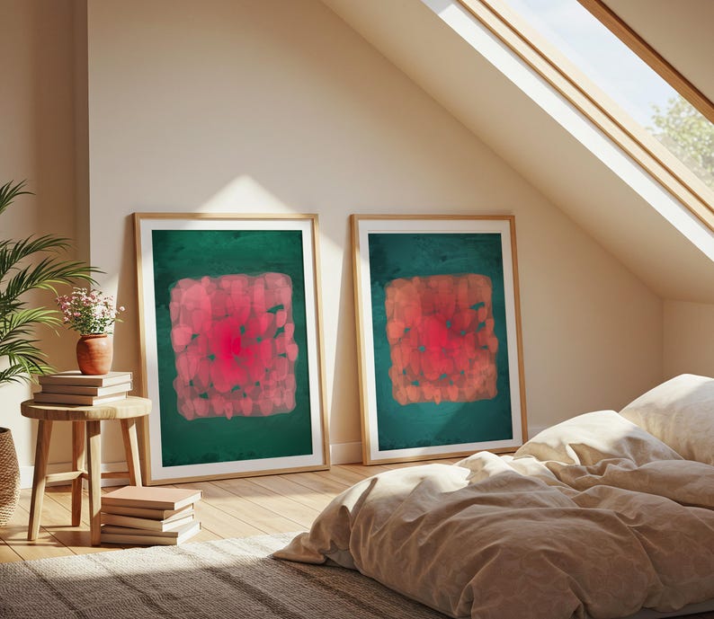 May include: Two framed abstract art prints. Each features a central, textured, red and pink square on a dark green background. The frames are light wood, and the art is displayed in a room with a bed and a skylight.