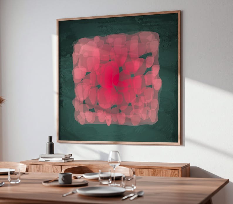 May include: A framed abstract art piece with a dark green background and a central design of overlapping pink shapes. The artwork is displayed above a wooden dining table set with plates, glasses, and silverware.