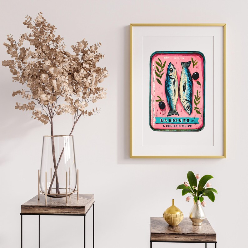 May include: A vintage-style illustration of a can of sardines in olive oil. The can is pink with blue and white lettering that reads "SARDINES A L'HUILE D'OLIVE". The illustration is framed in a gold frame.
