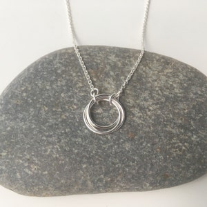 May include: A silver necklace with a pendant made of four interlocking circles.