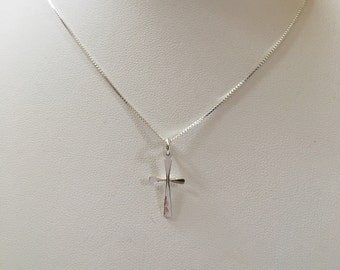 May include: A silver chain necklace with a small silver cross pendant.
