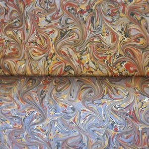 Può includere: Primo piano di un foglio di carta marmorizzata con motivi a spirale in tonalità di rosso, giallo, blu e grigio.