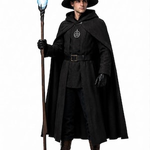 Pode incluir: Uma capa preta com capuz, uma túnica preta com cinto, calças pretas e um chapéu pontudo. O traje inclui um pingente prateado, luvas pretas e botas castanhas. Um longo cajado de madeira com uma esfera azul brilhante é segurado na mão.