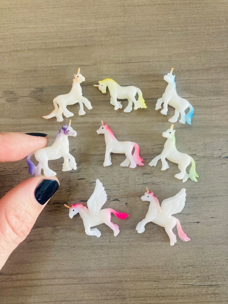 Peut inclure: Un ensemble de neuf petites figurines de licorne blanches avec des cornes dor&eacute;es. Les licornes ont des accents de couleurs diff&eacute;rentes, notamment rose, violet, bleu et jaune. Certaines des licornes ont des ailes.
