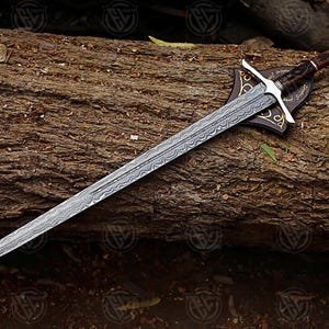 Puede incluir: Una espada larga y plateada con una hoja estampada, apoyada sobre un tronco de madera texturizado. La empu&ntilde;adura es marr&oacute;n con una guarda plateada y una placa decorativa. El dise&ntilde;o de la espada sugiere un tema hist&oacute;rico o de fantas&iacute;a.