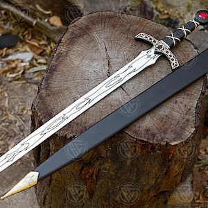 May include: A medieval sword with a silver blade and decorative patterns, a black handle with a crisscross design, and a red gem on the pommel. The sword lies on a wooden stump beside a black sheath with a gold tip.