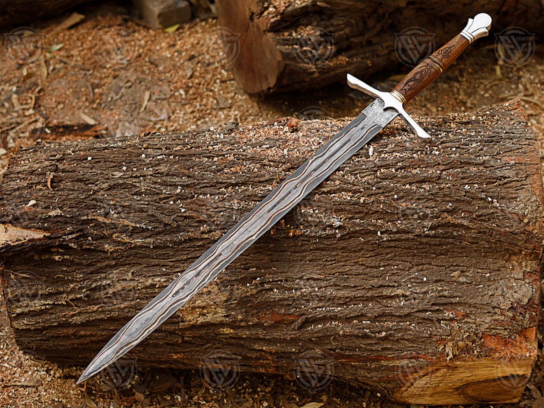 Puede incluir: Una espada larga y ornamentada con una hoja estampada y un mango de madera. La empu&ntilde;adura es plateada con una guarda cruzada. La espada descansa sobre un tronco desgastado, mostrando su detallada artesan&iacute;a.