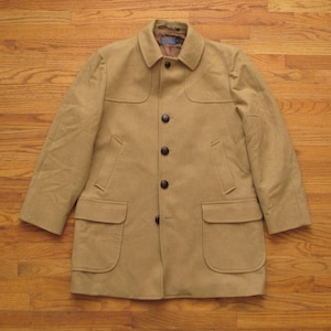 May include: A tan, button-down coat with a classic design. The coat features a notched collar, two front pockets, and four dark brown buttons. The coat is made of a soft, textured fabric.