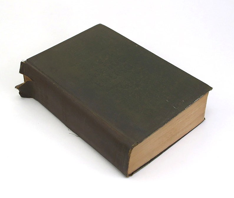 Op de afbeelding: Een donkergroen hardback boek met een versleten leren omslag en een licht beschadigde rug.