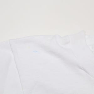 May include: White t-shirt with a small blue mark on the shoulder.