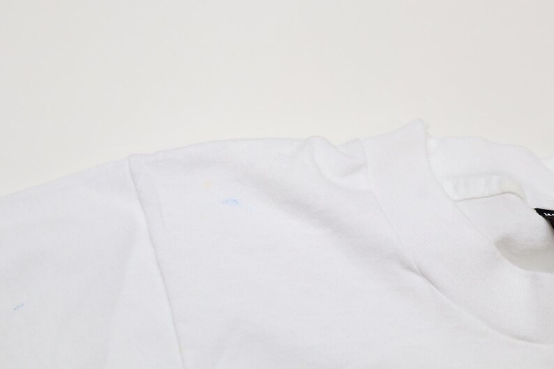 May include: White t-shirt with a small blue mark on the shoulder.