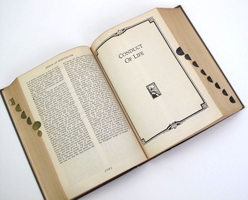 Op de afbeelding: Een open boek met een groene kaft en de titel "Conduct of Life" op de rechterpagina. De linkerpagina heeft de titel "Speech at Manchester" en gedrukte tekst.