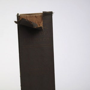 Op de afbeelding: Een bruin boek met een gescheurde kaft. De titel "A.D.  MORRISON" is zichtbaar op de rug.
