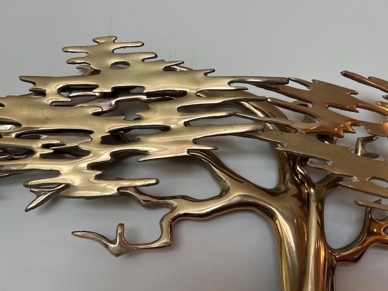 K&ouml;nnte beinhalten: Eine Baumskulptur aus Messing mit detailliertem Design. Die &Auml;ste und Bl&auml;tter des Baumes sind aufwendig geformt und erzeugen ein strukturiertes Aussehen. Die Skulptur hat eine polierte, goldene Oberfl&auml;che, die dem Kunstwerk einen Hauch von Eleganz verleiht.