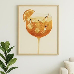 May include: Watercolor print of a large cocktail glass filled with an orange-colored liquid, ice cubes, and small figures swimming. A slice of orange sits on the rim. The artwork is framed and displayed in a living room setting.