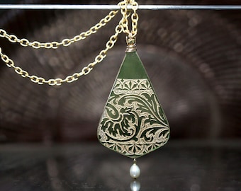 May include: A green glass pendant with a gold filigree design hangs from a gold chain. A single pearl dangles from the bottom of the pendant.