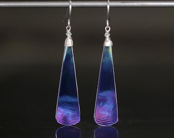 May include: A pair of silver dangle earrings with iridescent blue and purple teardrop-shaped stones.