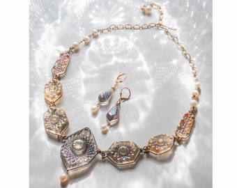 May include: A gold necklace with iridescent glass beads and pearl accents. Matching earrings with iridescent glass and pearl drops.