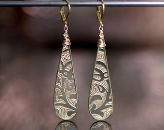 May include: Gold teardrop earrings with a delicate etched design and a clear crystal accent.