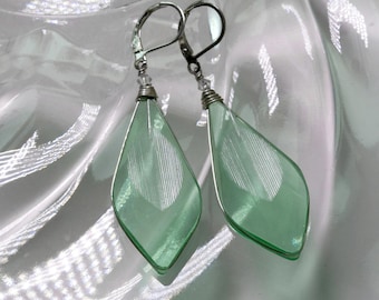 May include: A pair of silver dangle earrings with light green teardrop-shaped glass beads.