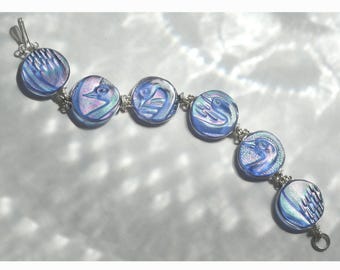 May include: A silver bracelet with iridescent blue glass beads featuring a carved design of birds.