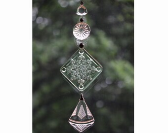 May include: A crystal suncatcher with a diamond-shaped piece, a round piece, and a teardrop-shaped piece hanging from a black string.