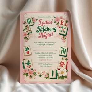 K&ouml;nnte beinhalten: Eine rosa Einladungskarte mit dem Text "Ladies' Mahong Night!" in Gr&uuml;n und Rosa. Die Karte zeigt florale Akzente und Illustrationen von Mahjong-Steinen. Die Einladung enth&auml;lt Veranstaltungsdetails.