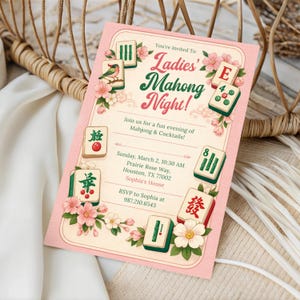 K&ouml;nnte beinhalten: Eine rosa Einladung mit dem Text "Ladies Mahjong Night!" und Illustrationen von Mahjong-Steinen. Die Einladung enth&auml;lt Veranstaltungsdetails wie Datum, Uhrzeit und Ort. Die Einladung liegt auf einem wei&szlig;en Tuch mit einem geflochtenen Korb im Hintergrund.