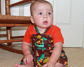 May include: A baby wearing a brown and orange outfit with a dinosaur print. The outfit has a halter top and a skirt. The baby is sitting on a brown carpet.