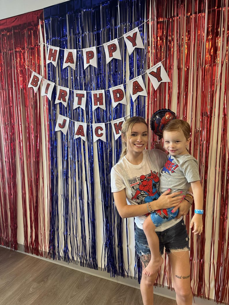 Puede incluir: Una mujer y un ni&ntilde;o frente a una cortina de l&aacute;minas rojas, blancas y azules. Una pancarta dice "HAPPY BIRTHDAY JACK". La mujer y el ni&ntilde;o llevan camisetas. El ni&ntilde;o lleva una camiseta de Spider-Man.