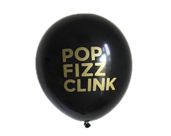 May include: Black balloon with gold lettering that reads "POP FIZZ CLINK".