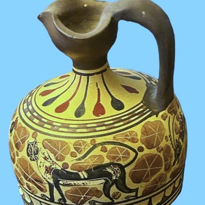 May include: A ceramic jug with a rounded body and a curved handle. The jug features a yellow background with brown and red decorative patterns and a black figure. The spout is brown.