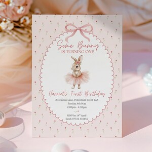 May include: A pink invitation card with a bunny illustration, text that reads "Some Bunny Is Turning One" and "Harriet's First Birthday". The card has a scalloped border and floral accents.