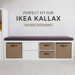 May include: A white storage bench with a dark purple cushion top. It features two white drawers and four natural jute baskets with brown leather handles. The text on the wall says "PERFECT FIT FOR IKEA KALLAX".