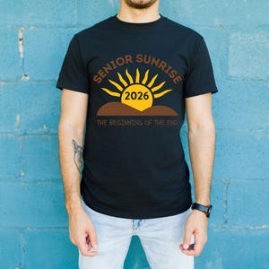 May include: Black t-shirt with a graphic design featuring the words "SENIOR SUNRISE 2026" in brown and yellow, with a sun graphic. The text "THE BEGINNING OF THE END" is below the sun graphic.