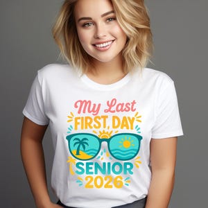Peut inclure: T-shirt blanc avec l'inscription "My Last First Day SENIOR 2026" en rose, jaune et turquoise. Le motif comprend des lunettes de soleil avec un palmier et un soleil.