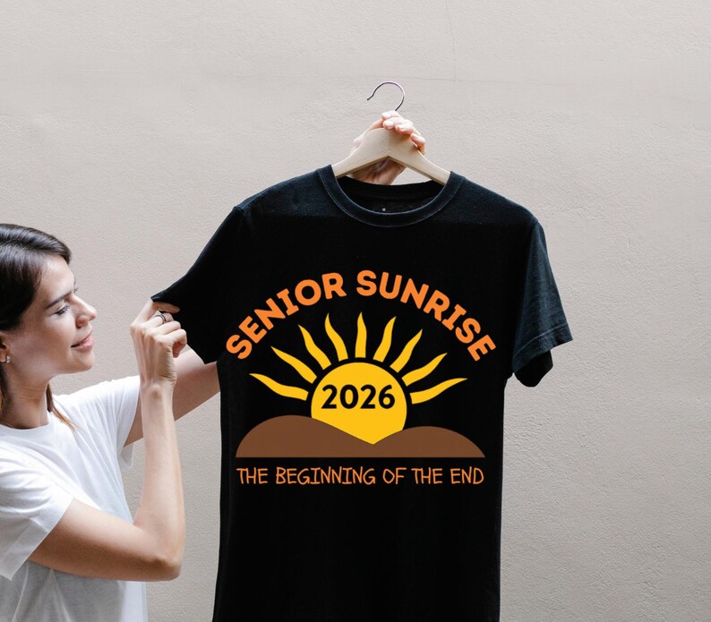 May include: Black t-shirt with the words "SENIOR SUNRISE 2026" in orange and yellow. The design features a sun graphic above a brown line, with the phrase "THE BEGINNING OF THE END" below.