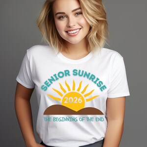 May include: White t-shirt with the words "SENIOR SUNRISE" in teal, a yellow sun graphic, and the year "2026" in yellow. Below the sun is a brown hill graphic and the text "THE BEGINNING OF THE END" in teal.