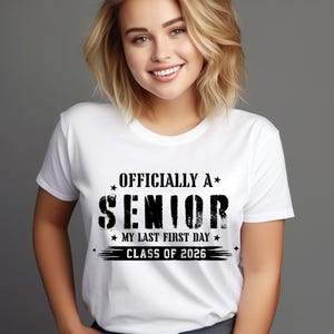 Peut inclure: T-shirt blanc à col rond avec l'inscription noire "OFFICIALLY A SENIOR", ainsi que "MY LAST FIRST DAY" et "CLASS OF 2026". Le t-shirt a un style classique et décontracté.